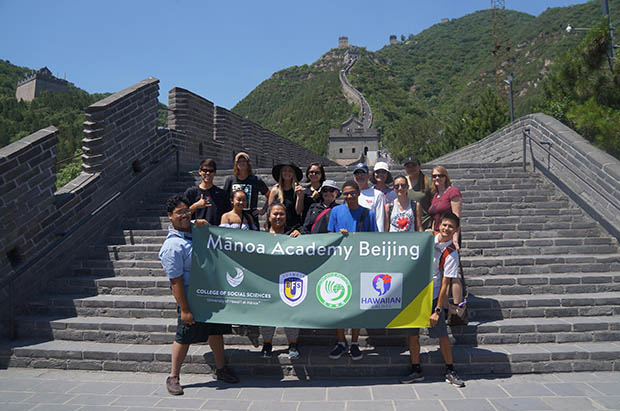 Manoa Academy Beijing students holding a banner at the Great Wall of China