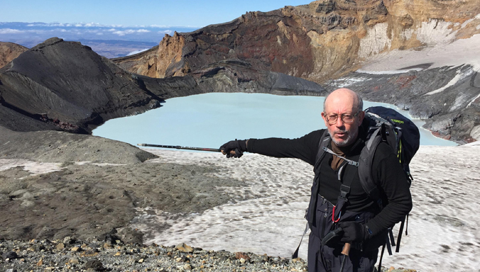 Houghton pointing a stick at a water-filled crater