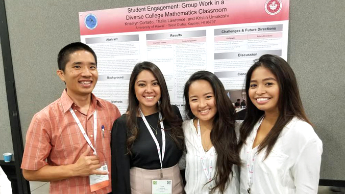 A teacher and 3 students in front of a science poster