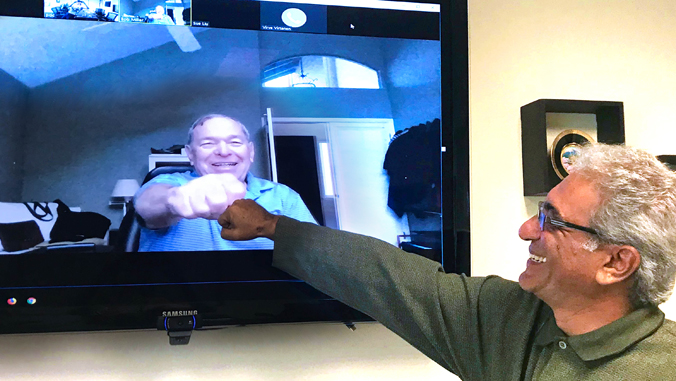 two people fist bumping over video conference