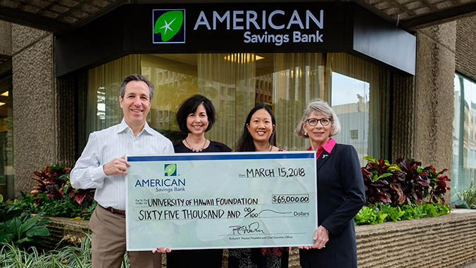 Four people holding an American Savings Bank check