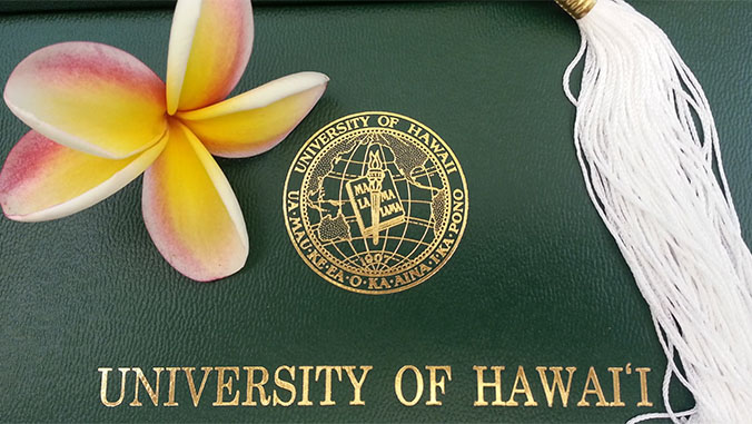 Cover of a U H Manoa diploma with a white tassel and plumeria