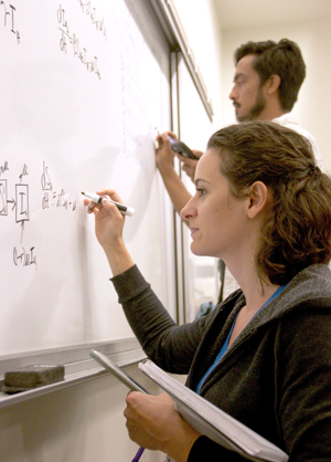students writing math equation on a white board