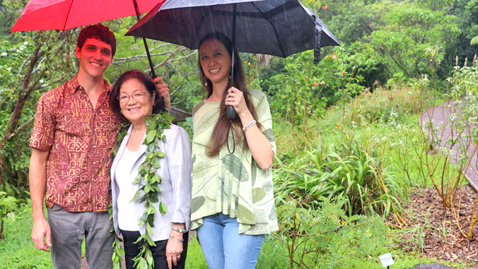 three people under umbrellas in the rain at the arboretum