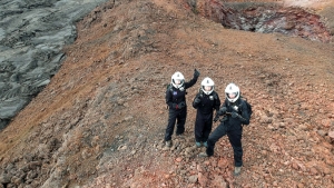 Researcher in space suits waving to drone flying above them