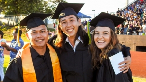 three students in graduation regalia