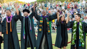 students in graduation regalia holding hands