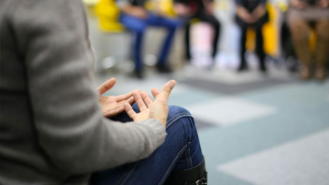 An unidentified person's hands in a circle discussion