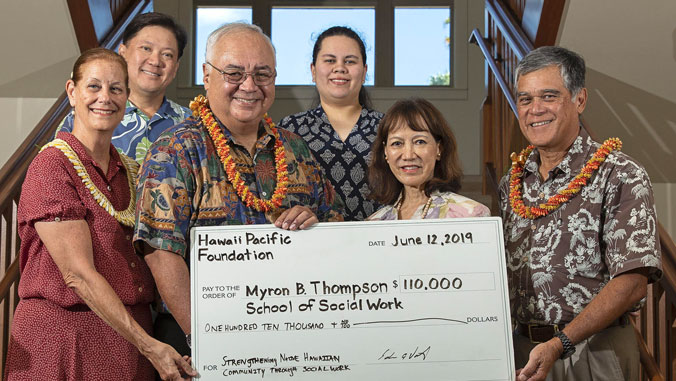 Group of people holding large check for $110,000