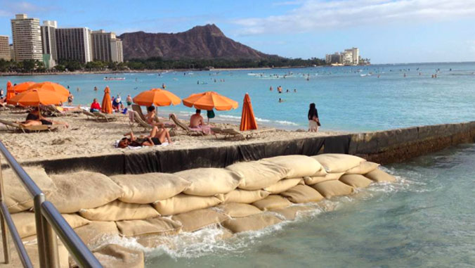 Sunbathers on Waikīkī Beach with sand bags piled up
