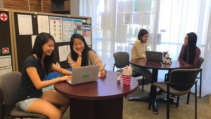 Students sitting at tables looking at laptops