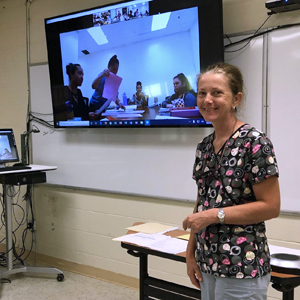 Mathis with screen with students behind her
