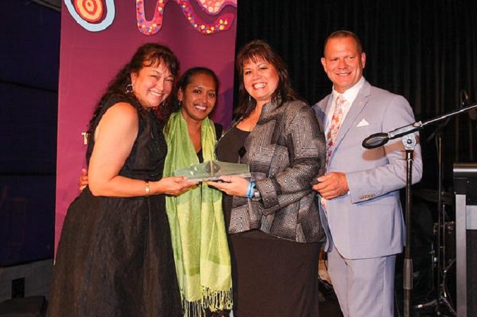 three ladies and a male representative holding award