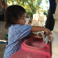 girl washing hands at toy sink