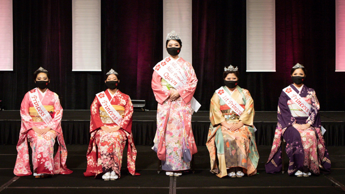 five people in kimono and face masks looking at the camera