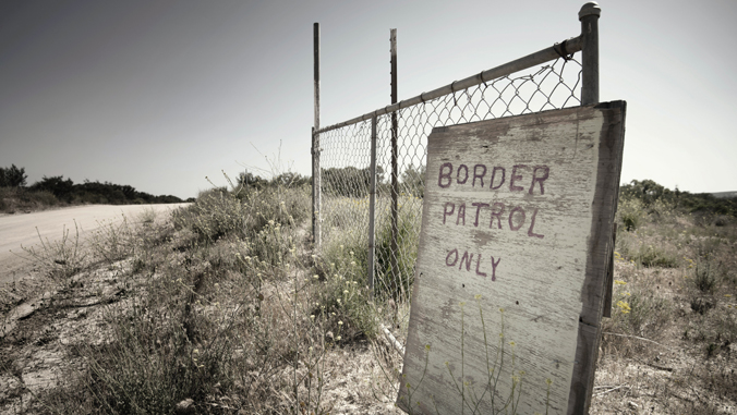 sign reading border patrol only leans against a fence in the desert