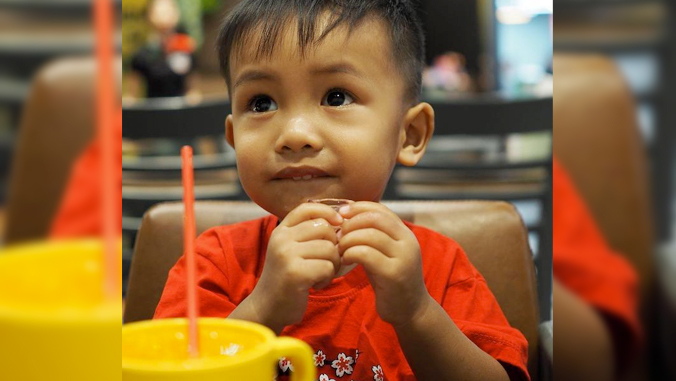 toddler boy with beverage in front of him