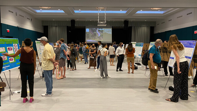 people standing in front of poster boards in a ballroom