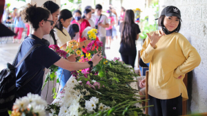Person flashing shaka at a table full of flowers. Other people are selecting flowers for their arrangements