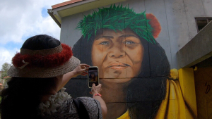 Woman taking a picture of the Edith Kanakaole mural