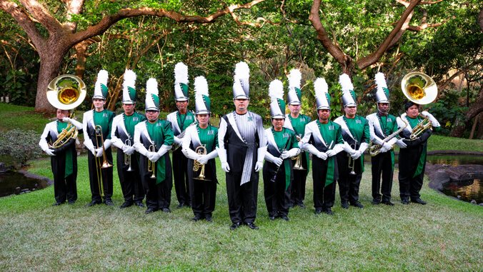people lined up with instruments and green uniforms with white feathers