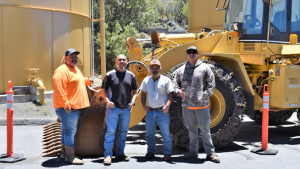 Four men standing in front of utility vehicle