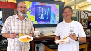 Two people holding plate with paint on it