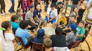 student sitting around a drum