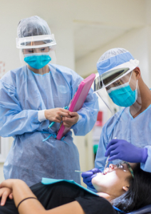 dental hygiene students cleaning a patient's teeth