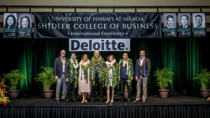 people standing on a stage with lei