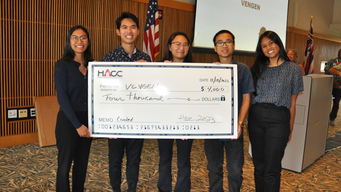 people smiling holding a large check