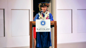 Kapiolani C C graduate delivering speech at podium