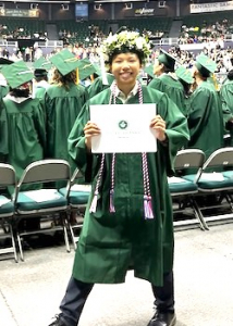 ongsy wearing her cap and gown and holding up dipoma