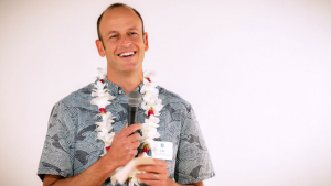 person wearing lei and speaking into microphone