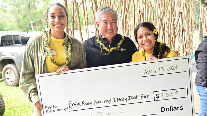 three people holding big check