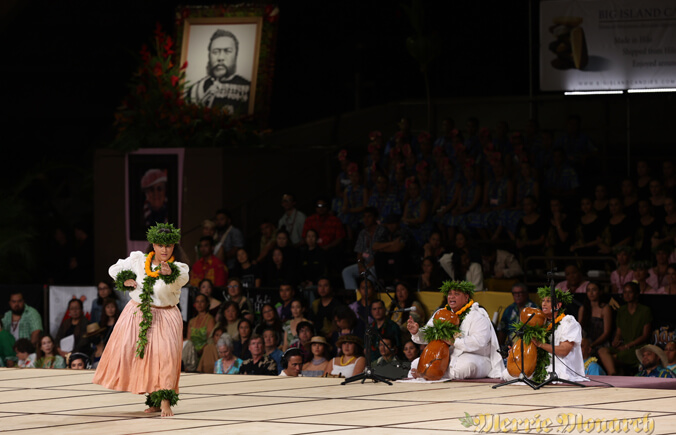 Lopes dancing at Merrie Monarch. A portrait of King Kalakaua hangs above the stage