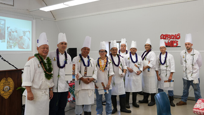 People in culinary outfits with certificates