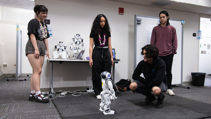 Four students standing around a robot