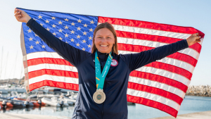 person smiling with a medal and a flag