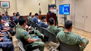 military people watching person at podium