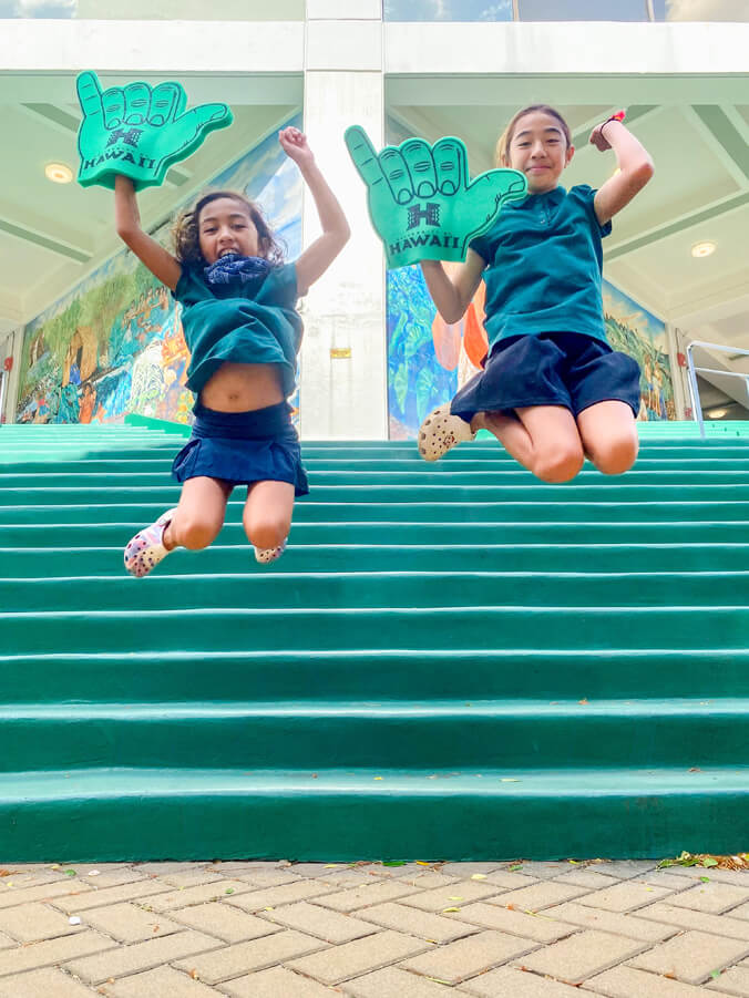 Two girls jumping at campus center