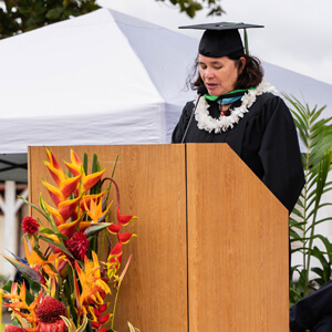 Margaret Sanchez in cap and gown behind a podium