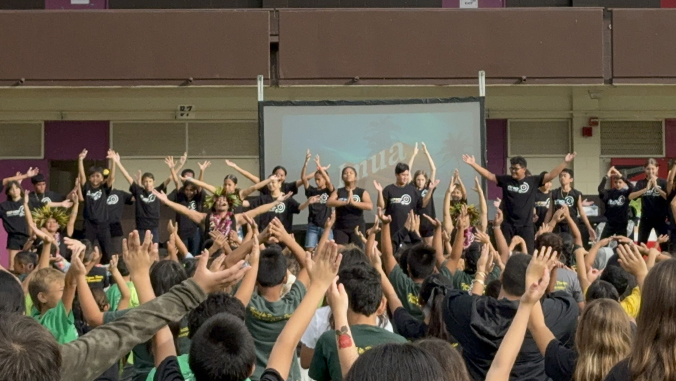 dozens of students clapping above their heads