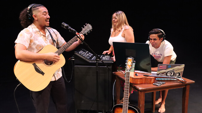 Three people with musical instruments and music recording equipment