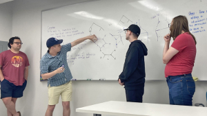 people drawing equations on a board