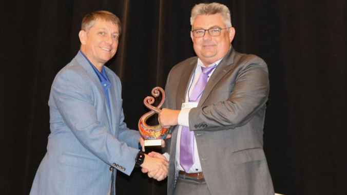 person smiling holding an award