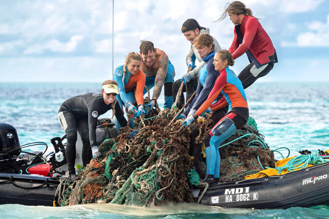 people on a boat pulling out marine debris