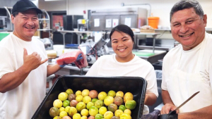 3 people holding a large pan of lilikoi