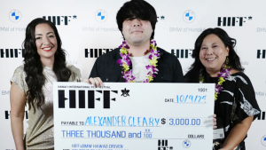 3 people standing in front of H I F F white background, one holding big check