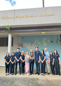 people standing and smiling in front of a new sign